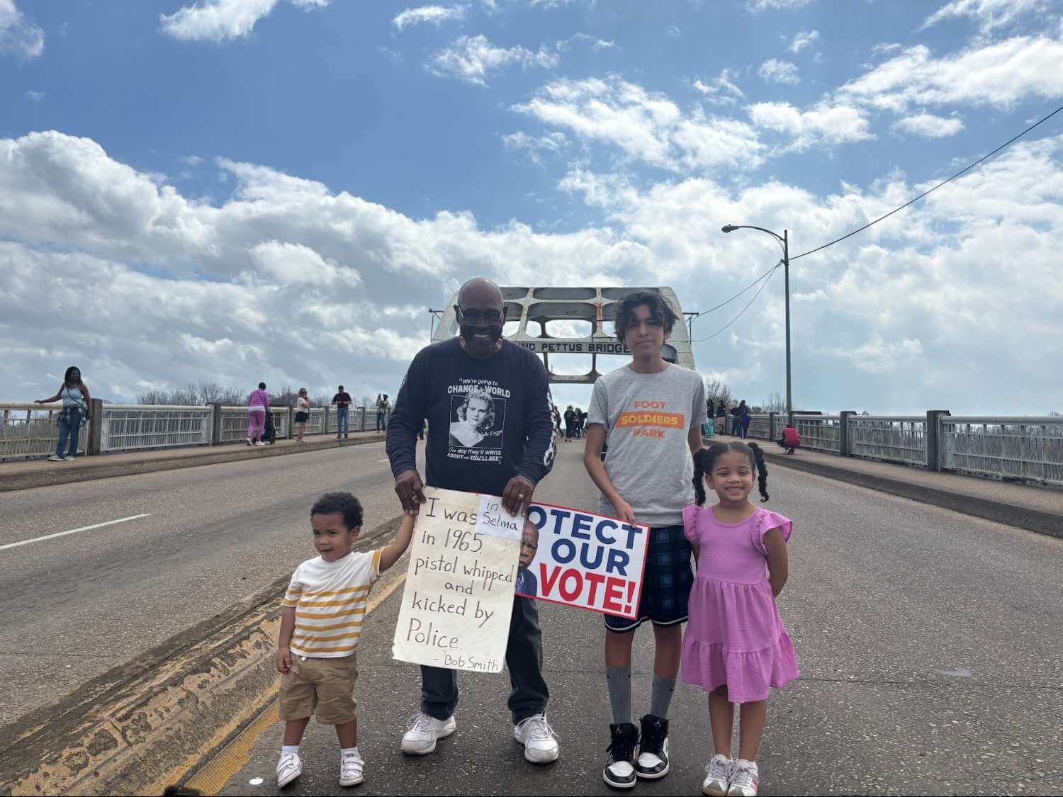 Selma Civil Rights Foot Soldier and icon, Mr. Bob Smith, stands proudly with his beautiful grandchildren in front of the Edmund Pettus Bridge in Selma, Alabama.